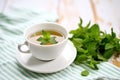 peppermint tea in cup with fresh mint bundle, white cloth