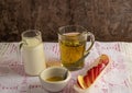 Peppermint tea, with floating mint leaves, in a clear glass cup, a jug with cow`s milk, red apple Royalty Free Stock Photo