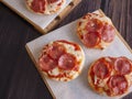 Pepperoni and Mozzarella Cheese Mini Pizzas served on Wooden Plates over White Food Paper