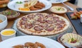 Pepperoni pizza with along with other arab cuisine items on the table