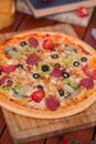 Pepperoni pizza with bell pepper, tomato slices, mushroom and olives.