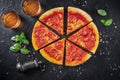 Pepperoni pizza on a black background, with wine glasses, basil, salt and pepper Royalty Free Stock Photo