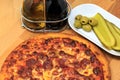 A pepperoni pizza with pickle and olives as a side Royalty Free Stock Photo