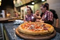 Pepperoni pizza on a wooden plate.