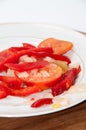 Peppers, tomatoes and onions cut for cooking on a plate