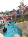 Children and adult tourists enjoying leisure activities having fun playing around resort water park Royalty Free Stock Photo