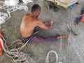 Ctivity of fisherman knitting or repairing their fishing net at the harbor dock