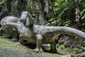 Two huge forest tree root sprouting out of the ground with a sauropod-shaped dinosaur