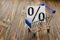 Percentages in shopping cart on wooden background