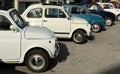 Row of white and blue vintage Fiat 500 at the roadside during a collector\'s car gathering.