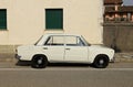Vintage white Fiat 124 Special, family car from Sixties and Seventies, at the roadside.