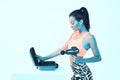Percussion massager, athletic young fit female posing with handheld massaging gun in neon studio light