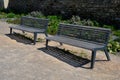 Perennial bed mulched with gray gravel in front of a limestone stone wall in a square with benches with wood paneling, beige path