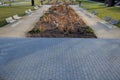 Perennial bed mulched with gray gravel in front of a limestone stone wall in a square with benches with wood paneling, beige path