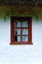 Detailed view of window of ancient clay house. White wall is decorated by authentic paints Royalty Free Stock Photo