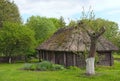 Landscape view of ancient traditional ukrainian barn with a straw roof and wicker walls. Trees in the background