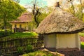 Wide angle landscape view of ancient clay house under thatched roof with a garden surrounded by a wicker fence in sunny day Royalty Free Stock Photo