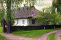 Wide angle landscape view of ancient clay house under thatched roof with a garden surrounded by a wicker fence. Royalty Free Stock Photo