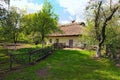 Wide angle landscape view of small ancient clay house with a garden surrounded by a wicker fence in sunny day Royalty Free Stock Photo