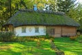 Ancient clay house with thatched roof and front yard with flower bed Royalty Free Stock Photo