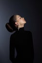 Perfect art woman in black turtleneck on a dark background. Brunette long hair is pulled into a bun. Evening makeup Royalty Free Stock Photo