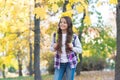 Perfect autumn day of cheerful kid with school bag walking in fall season park in good weather, happy childhood Royalty Free Stock Photo