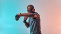 Perfect biceps. Muscular young african man exercising with dumbbells while standing against colorful background Royalty Free Stock Photo