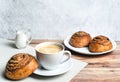 Perfect breakfast of a homemade cinnamon buns, coffee and glass milk jug on wooden table. Rustic style. Royalty Free Stock Photo