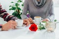 Perfect breakfast of romantic couple concept. Cropped insta shot of hands holding cups of coffee, beautiful flower and Royalty Free Stock Photo