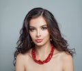 Perfect brunette model woman with makeup, long curly hair and red coral necklace