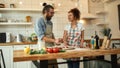 The perfect chef. Young couple making pizza together at home. Man in apron adding mozzarella cheese on the dough while