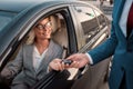 Perfect choice. Young beautiful woman in classic wear getting the car key and smiling while sitting in her new car Royalty Free Stock Photo