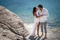 Perfect couple portrait, standing on stone beach behind mediterranean sea, honeymoon in Greece. Royalty Free Stock Photo