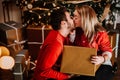 Couple wearing red sweaters, kissing and opening santa presents on Christmas morning