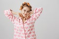 Perfect day for beauty therapies. Studio shot of good-looking ordinary girl at home, wearing hair curlers and pyjamas Royalty Free Stock Photo