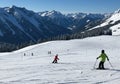 Children Enjoying Skiing Down a Snow Covered Mountain Slope with Majestic Peaks in Background Royalty Free Stock Photo