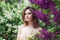 Perfect female face in lilac flowers garden. Pretty woman on floral background