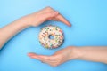 Perfect food creating concept. Photo of tasty donut with colorful sprinkles and two hands making roof catching the flying object Royalty Free Stock Photo