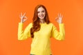 Perfect idea concept, acception. Good-looking redhead girl in yellow sweater, showing okay, good or approval sign