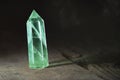 Perfect large shining crystal transparent colored green emerald. Natural quartz in light on wooden background close up
