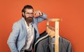 Perfect male. Large selection of mens suits. bearded man choose jacket on hanger. male wardrobe concept. man go shopping