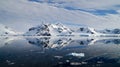 Perfect mirror reflections of snowy mountains and icebergs in Antarctica.