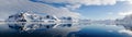 Perfect mirror reflections of snowy mountains and icebergs in Antarctica.