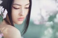 Portrait of a beautiful fantasy asian girl outdoors against natural spring flower background. Royalty Free Stock Photo