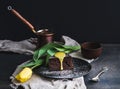 Perfect morning set for woman. Piece of truffle chocolate cake with lemon curd icing, hot coffee and yellow tulip on dark backdrop Royalty Free Stock Photo