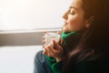 Perfect morning A young brunette woman sits on a windowsill and holds a cup of tea or coffee in her hands. Female model Royalty Free Stock Photo