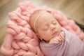 Perfect newborn baby girl in pink blanket in a wicker basket decorated with beautiful pink tulips