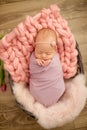 Perfect newborn baby girl in pink blanket in a wicker basket decorated with beautiful pink tulips