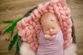 Perfect newborn baby girl in pink blanket in a wicker basket decorated with beautiful pink tulips