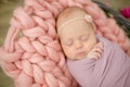 Perfect newborn baby girl in pink blanket in a wicker basket decorated with beautiful pink tulips